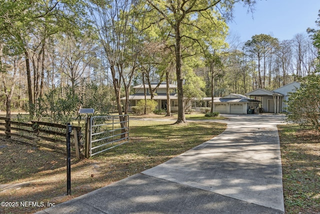 view of front of home featuring a front yard, a gate, fence, an attached garage, and concrete driveway