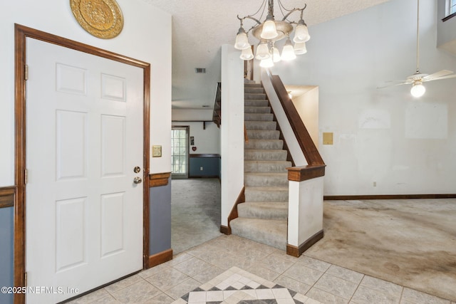 foyer entrance with visible vents, a textured ceiling, stairway, light tile patterned floors, and light colored carpet