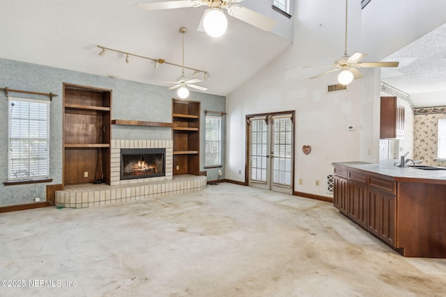 unfurnished living room featuring visible vents, wallpapered walls, baseboards, light carpet, and a sink