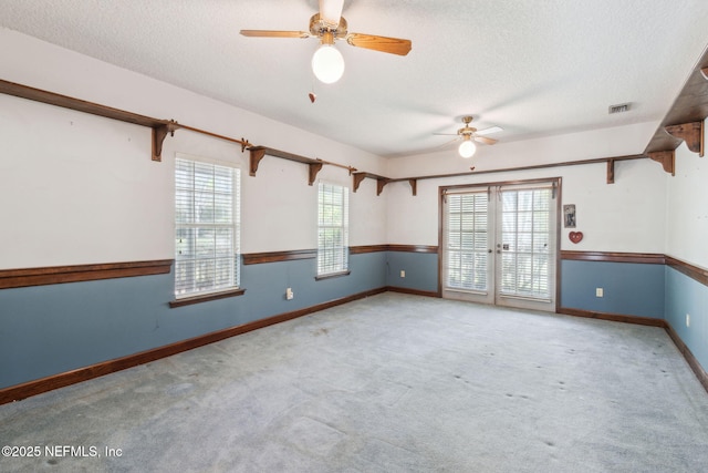 spare room with carpet, baseboards, visible vents, french doors, and a textured ceiling