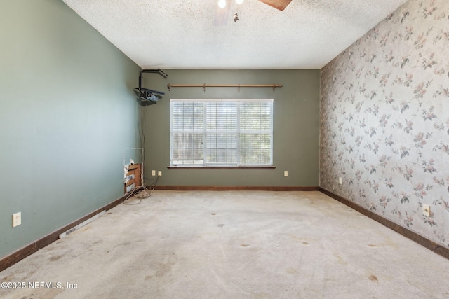 spare room with carpet flooring, a textured ceiling, wallpapered walls, and baseboards