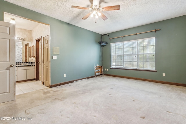 unfurnished room with ceiling fan, carpet flooring, baseboards, and a textured ceiling