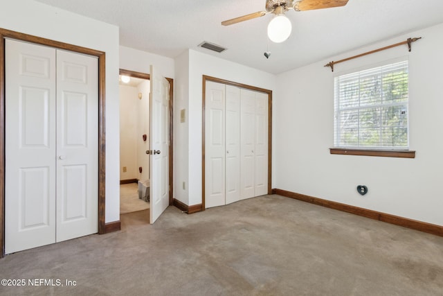 unfurnished bedroom with visible vents, two closets, ceiling fan, baseboards, and carpet floors