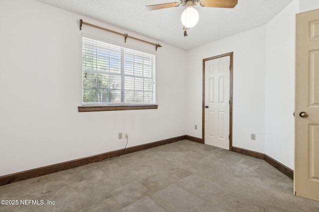 carpeted empty room featuring ceiling fan, baseboards, and a textured ceiling