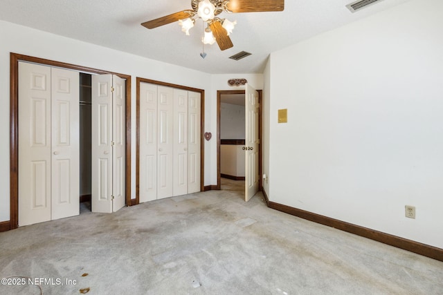 unfurnished bedroom featuring visible vents, carpet floors, two closets, and baseboards