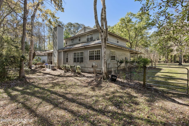 back of house with metal roof, fence, and a chimney