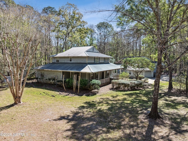 rear view of property featuring a garage, a porch, metal roof, and a yard