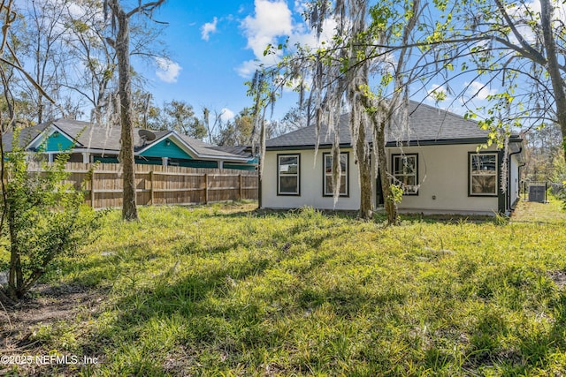 back of house featuring stucco siding, roof with shingles, and fence