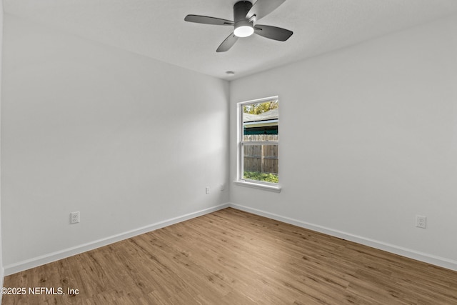 empty room featuring wood finished floors, baseboards, and ceiling fan