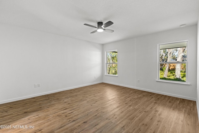 unfurnished room with a ceiling fan, wood finished floors, and baseboards