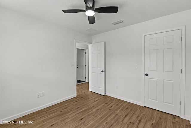 unfurnished bedroom with ceiling fan, visible vents, baseboards, and wood finished floors