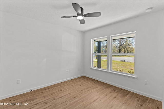 empty room with ceiling fan, light wood-type flooring, and baseboards