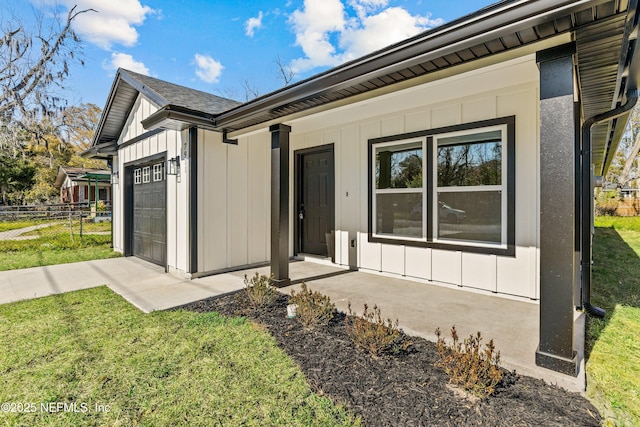 view of front facade with a front yard, board and batten siding, an attached garage, and fence