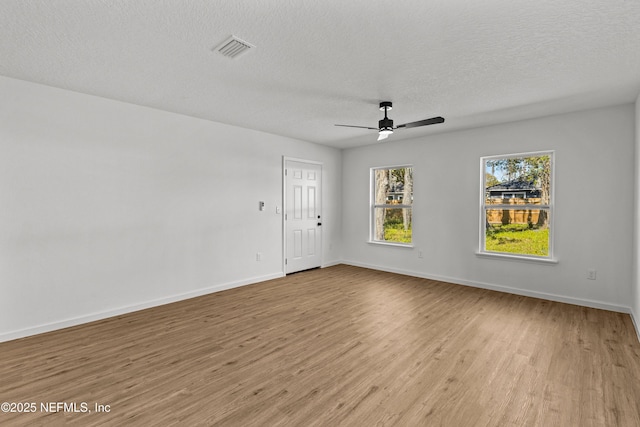 empty room with visible vents, baseboards, light wood-style floors, and ceiling fan