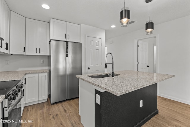 kitchen with a sink, appliances with stainless steel finishes, light wood-style flooring, and white cabinets