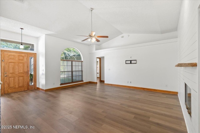 unfurnished living room featuring a large fireplace, wood finished floors, a textured ceiling, high vaulted ceiling, and a ceiling fan