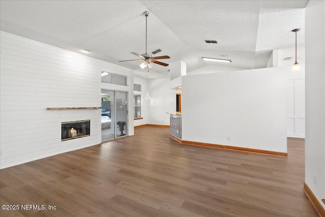 unfurnished living room with visible vents, a ceiling fan, a textured ceiling, wood finished floors, and a fireplace