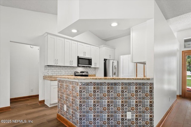 kitchen featuring dark wood-type flooring, appliances with stainless steel finishes, white cabinets, decorative backsplash, and baseboards