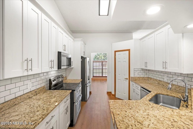 kitchen featuring light stone countertops, appliances with stainless steel finishes, white cabinetry, and a sink