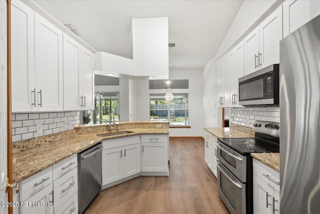 kitchen with white cabinets, light wood-style floors, appliances with stainless steel finishes, and a sink