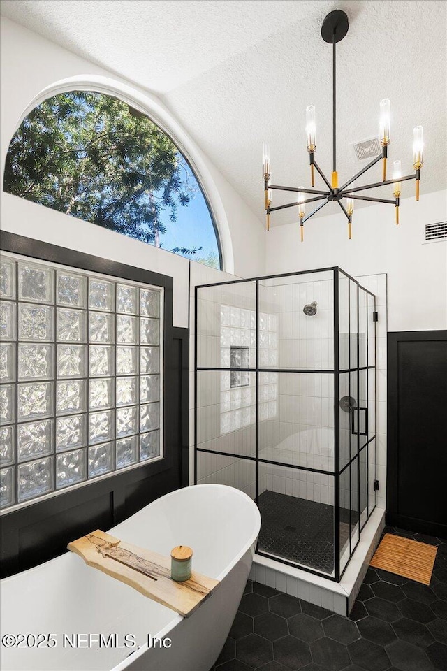 full bath featuring lofted ceiling, a soaking tub, tile patterned flooring, a shower stall, and a textured ceiling