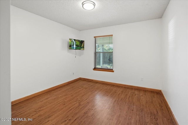 unfurnished room featuring baseboards, a textured ceiling, and wood finished floors