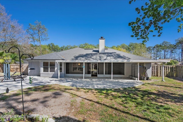 back of property featuring a patio, fence, a sunroom, a chimney, and a lawn