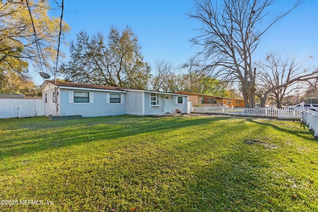 rear view of house featuring a lawn and a fenced backyard