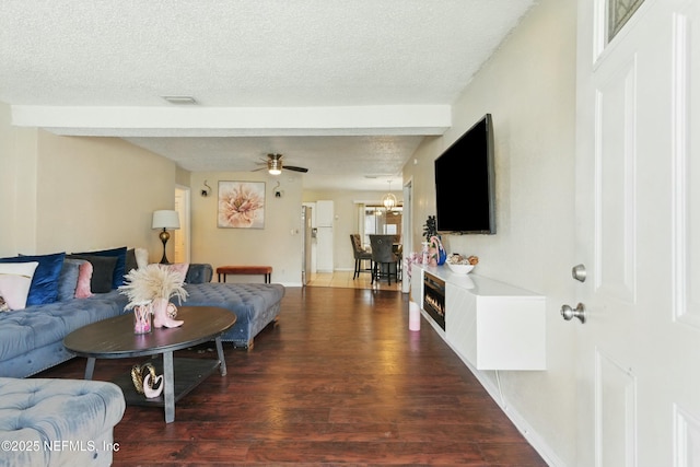 living room with visible vents, baseboards, a lit fireplace, wood finished floors, and a textured ceiling