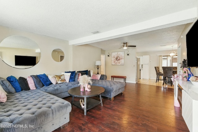 living area featuring ceiling fan with notable chandelier, wood finished floors, visible vents, and a textured ceiling