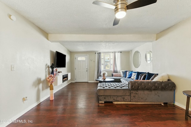 living room featuring a glass covered fireplace, baseboards, a textured ceiling, and wood finished floors