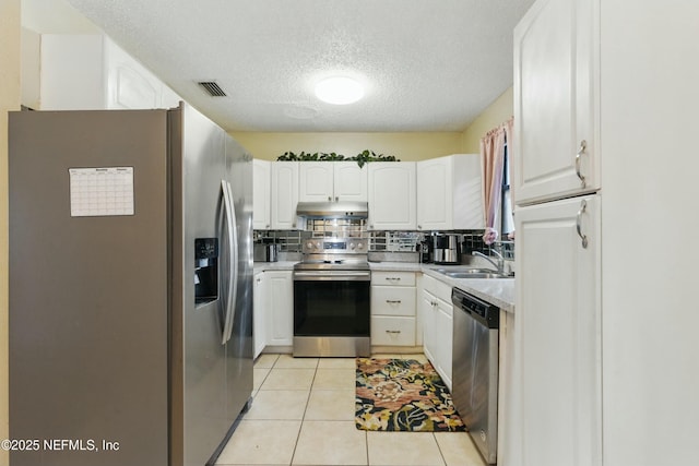 kitchen with visible vents, under cabinet range hood, appliances with stainless steel finishes, white cabinetry, and a sink