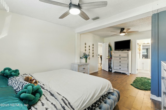 bedroom with visible vents, a ceiling fan, a textured ceiling, ensuite bath, and wood finished floors