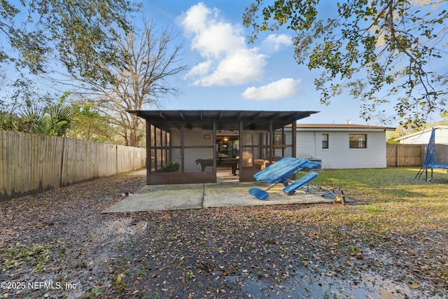 back of property with a trampoline, a fenced backyard, a yard, a sunroom, and a patio area