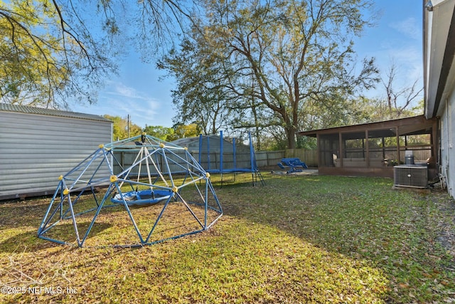 view of yard with a fenced backyard, central AC unit, and a trampoline