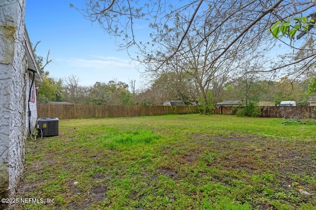 view of yard with a fenced backyard and central AC