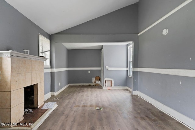 unfurnished living room with baseboards, lofted ceiling, wood finished floors, and a fireplace