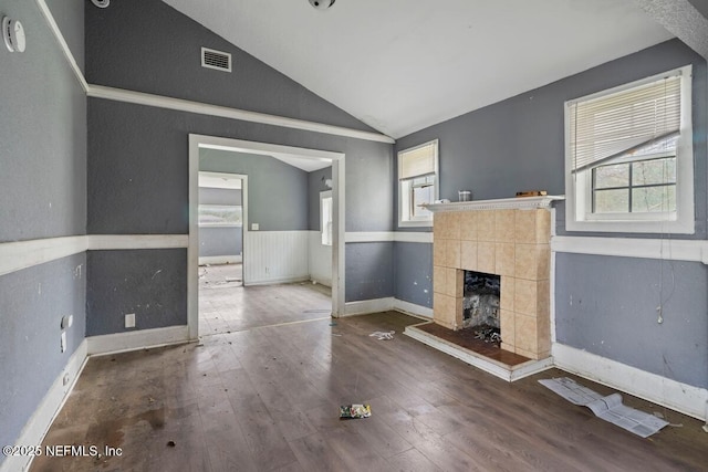 unfurnished living room featuring visible vents, a healthy amount of sunlight, hardwood / wood-style floors, and vaulted ceiling