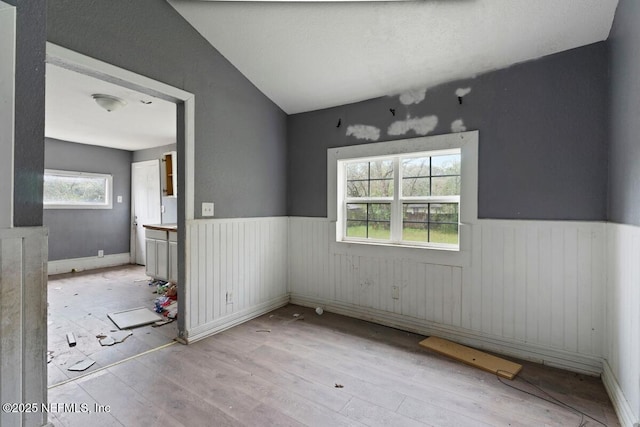 unfurnished dining area with wood finished floors and wainscoting