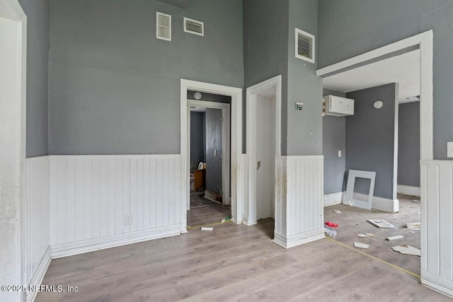 unfurnished room with visible vents, wood finished floors, and a wainscoted wall