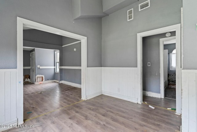 unfurnished room featuring a wainscoted wall, visible vents, and wood finished floors