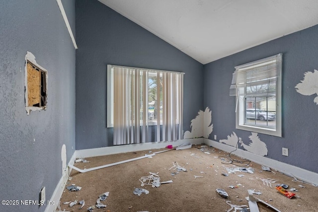 spare room featuring baseboards and vaulted ceiling