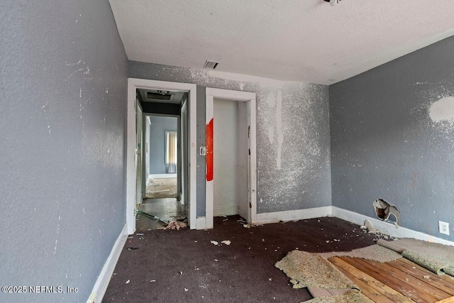 empty room with visible vents, baseboards, and a textured ceiling