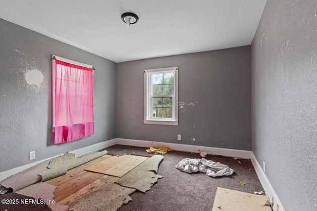 unfurnished room with baseboards, a textured ceiling, and a textured wall