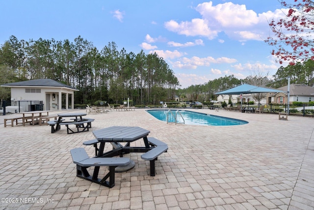 community pool with a patio area and fence