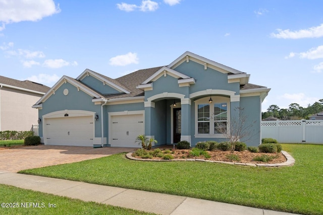 view of front of property featuring a front lawn, fence, stucco siding, decorative driveway, and a garage