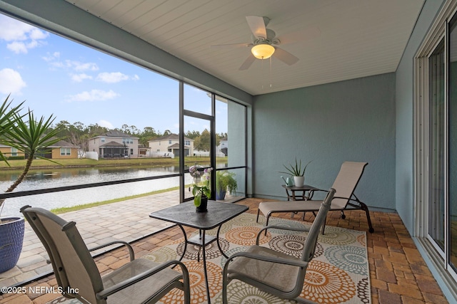 sunroom featuring a residential view, ceiling fan, and a water view