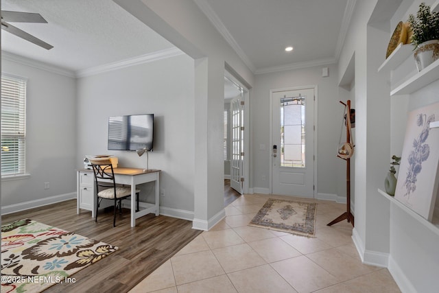 foyer featuring ceiling fan, baseboards, a wealth of natural light, and ornamental molding