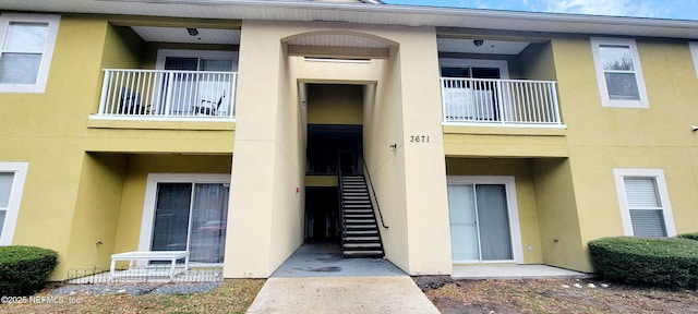 entrance to property with stucco siding and a balcony