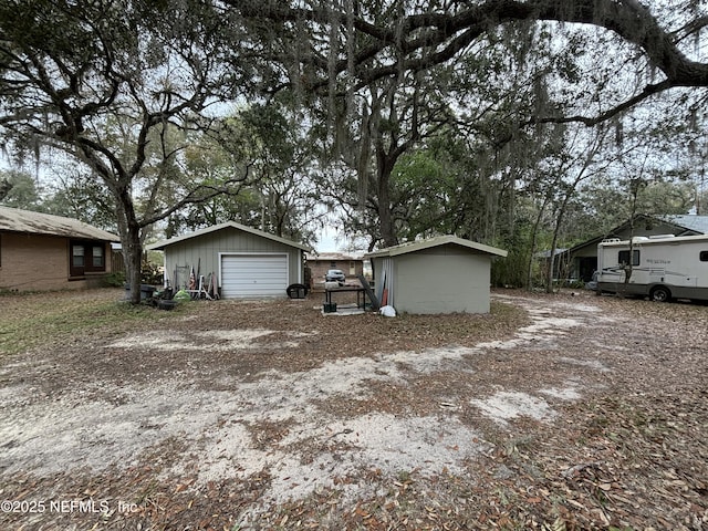 view of front of property with a detached garage, an outbuilding, and driveway